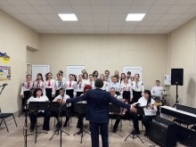 Диригент та музиканти на передньому плані, за ними стоїть хор