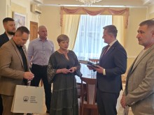 Наталія Чукова та представники Донеччини стоять біля посла, який тримає подаровану книгу.