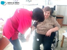 Представниця Червоного хреста, міряє тиск жінці похилого віку яка сидить у кріслі колісному