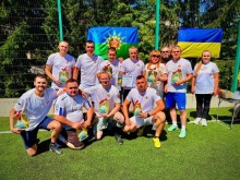 Спільне фото футбольної команди та представників влади. В руках тримають диплом та цінні призи з логотипом стели Донеччини.