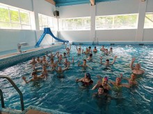 Група дітей в басейні машуть руками