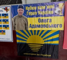 Стенд з назвою зазоду та фото Олега Адамовського та прапором Донеччини