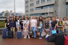 Спільне фото дітей та дорослих. На задньому плані будівля світлого кольору.
