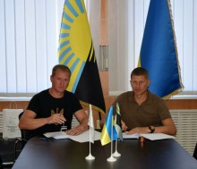 Підписання Меморандуму про співпрацю між Очеретинською селищною і Старобогородчанською сільською територіальними громадами. Голови громад сидять за столом, позаду них прапори Донеччини та України.