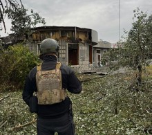 Правоохоронець стоїть біля зруйнованого будинку