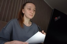 Модераторка зустрічі Катерина Зеленська сидить біля ноутбука з аркушем паперу та ручкою в руках