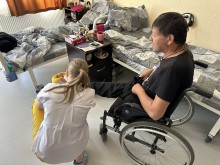 Лікар-подолог проводить огляд чоловічої ноги. Чоловік сидить у кріслі колісному.