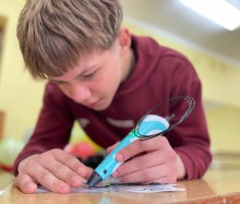 Хлопчик малює 3Д ручкою на аркуші паперу