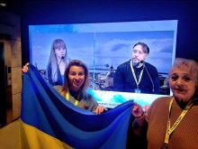 Онлайн зустріч. На екрані монітора актори. Попереду акторка театра тримає прапор України.