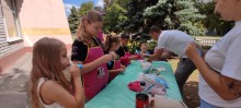 Діти стоять біля столу та починають надувати повітряні кульки для виготовлення  іграшки, психологи допомагають  дітям