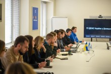 Учасники зустрічі сидять за столом.