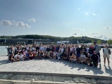 Велика група учасників проєкту «Грай за рівність» позує для фото біля водойми у Винниках на тлі футбольної академії «Рух».