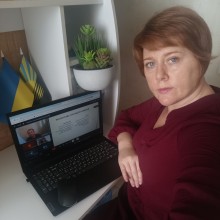 Представник військової адміністрації сидить за столом та слухає доповідача на семінарі