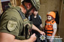 Евакуація малолітньої дитини разом з матір'ю. Дитина одягнена у бронежилет та каску помаранчевого кольору