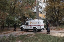 Рятувальники евакуаційної групи «ФЕНІКС» стоять біля броньованого автомобіля білого кольору.