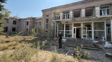 Правоохоронець стоїть біля зруйнованої окупантами будівлі школи