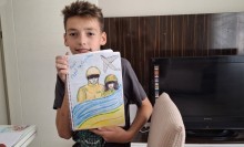 Хлопець, вихованець Донецького центру технічної творчості дітей та юнацтва, демонструє свій патріотичний малюнок до Дня Захисників і Захисниць України.