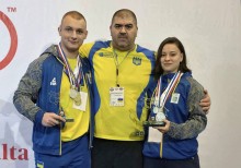 Українські спортсмени разом з тренером тримають нагороди