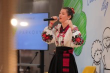 Дівчина у народному костюмі виконує пісню.