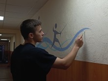 Студент розписує стіну спортивної школи силуетом фехтувальника в межах волонтерського мистецького проєкту від Краматорського коледжу.