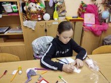 Дівчина за столом займається виготовленням поробки