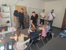 Наталія Чукова та представники делегації спілкуються з дітьми, які малюють, та тиснуть руку хлопцю.