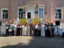 Випускники з дипломами та викладачі позують на фоні будівлі з написом "Випуск 2026"