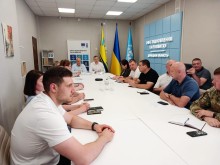 Учасники наради сидять за столом вся увага на центр стола, де стоять Юрій Винокуров та Владислав Лаврик.