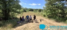 Велотуристи на привалі. З обох сторін ліс, над головами блакитне небо.