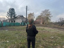 Правоохоронець стоїть на фоні зруйнованих ворогом будинків
