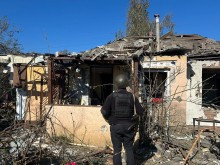 Зруйновані будинки після ворожого обстрілу та правоохоронець, який стоїть поруч з ними