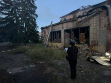 Правоохоронець стоїть біля адміністративної будівлі, зруйнованої окупантами.