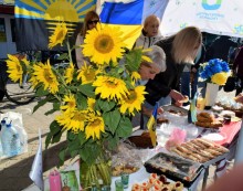 Ярмарок. Букет з соняшників на столі та їжа. Жінки за столом розкладають продукцію.