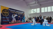 Спортсмени на спортивних матах, чекають початку змагань,поруч тренер.