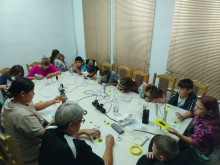 Діти та дорослі за великим столом створюють об'ємні соняшники за допомогою 3D-ручок