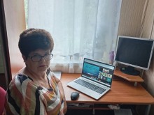 Представниця громади, яка приєдналась до онлайн вебінару. Поруч розташований відкритий ноутбук.