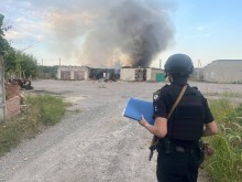 Правоохоронець стоїть на фоні пожежі, яку спричинив ворожий обстріл