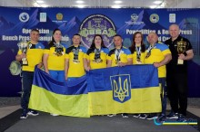 Українська команда спортсменів тримає кубок та прапори.