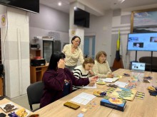 Жінки сидять за столом , уважно вивчають правила гри.