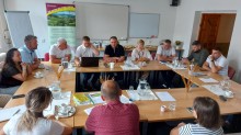 Делегація сидить за столом. Позаду мультимедійні екрани