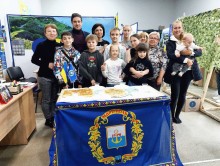 Група людей позує біля столу з логотипом Маріуполя