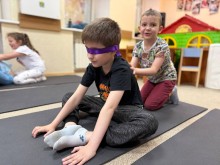 Хлопчик з пов'язкою на очах сидить на йога-маті
