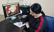 Учасник акції пише диктант перед екраном ноутбука