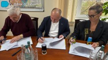 Представники громад сидять за столом тримають ручки у руках та підписують меморандуми.