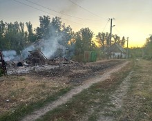 Обгорілий знищений обстрілом будинок дотліває через пожежу.