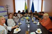 За столом сидять представники та голови громад, пригощаються пирогом.