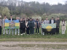 Учасники змагань стоять на футбольному полі та тримають прапори громад.