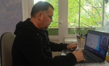 Представник військової адміністрації сидить за столом та слухає доповідача на семінарі