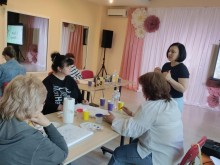 Співробітниця музею проводить майстер-клас для учасниць, які сидять за столами.