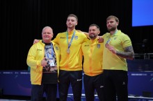 Українські спортсмени тримають медалі разом із власним тренером.
